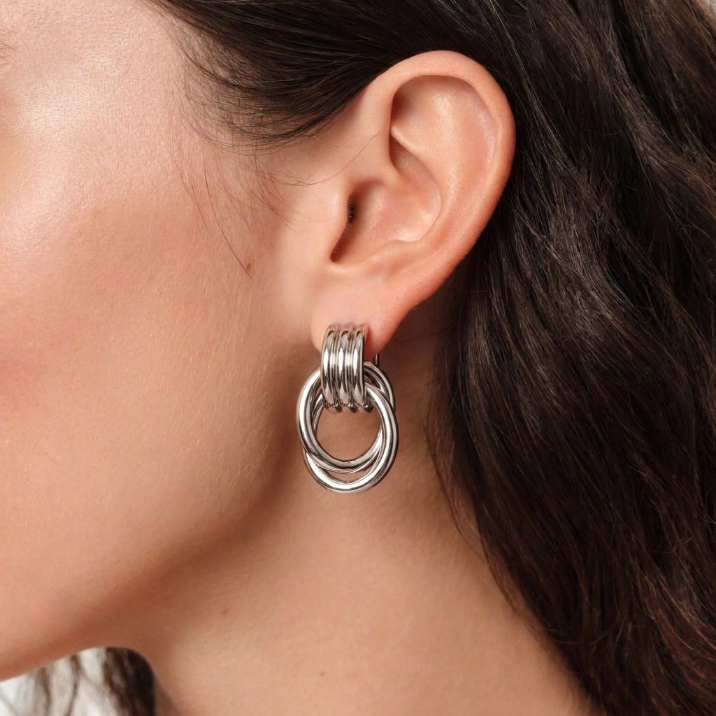 Pendientes de botón plateados con diseño de aros entrelazados y nudo geométrico en acero de titanio